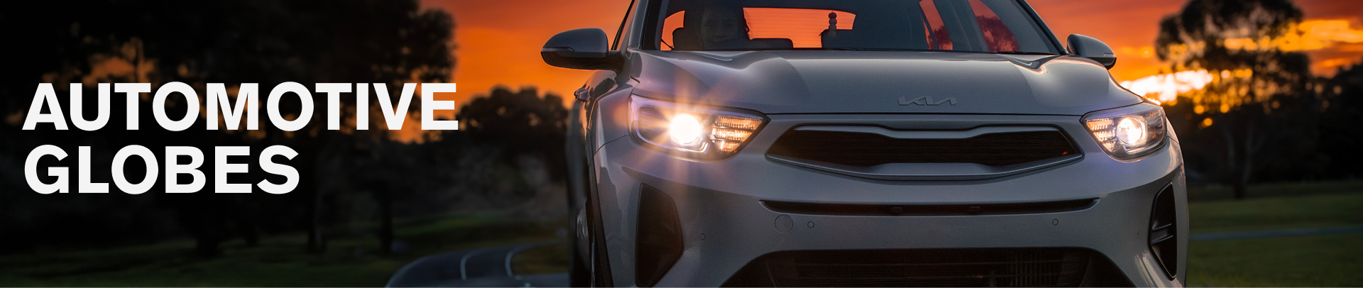 Vehicle with illuminated headlights at sunset